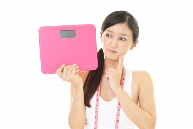 体重計を不安そうに眺める女性の画像です。パーフェクトボディプレミアムはリバウンドしないようにアドバイスをしてくれます。